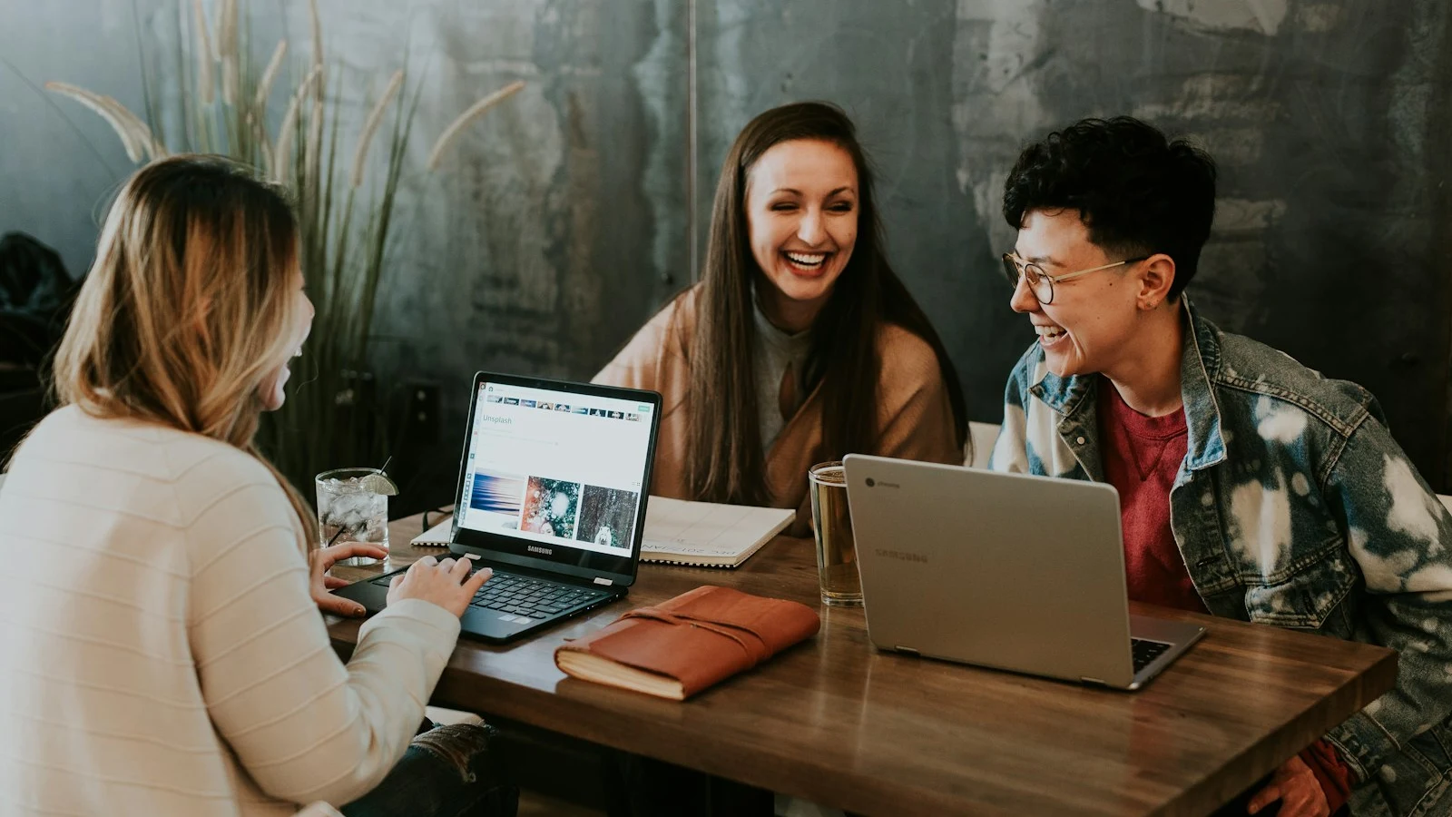 A small team collaborating around laptops in a warm workspace